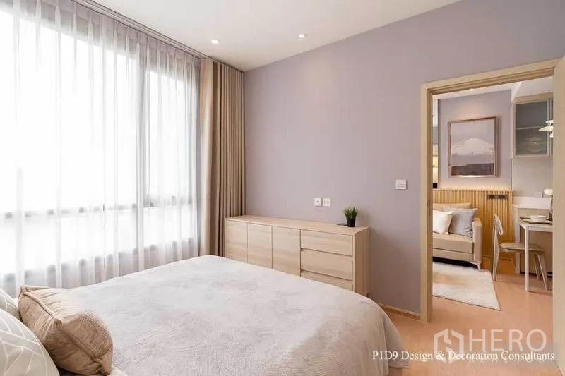 Condominium for rent in Watthana, Bangkok - Bright bedroom with large sheer‑draped window, low dresser and doorway leading to the living area.