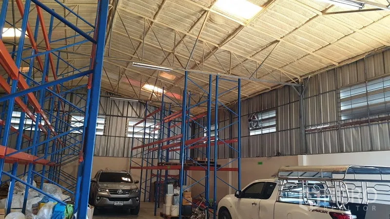 Warehouse for rent in Suan Luang, Bangkok - Spacious warehouse with racking rows and pickup trucks under a high ceiling.
