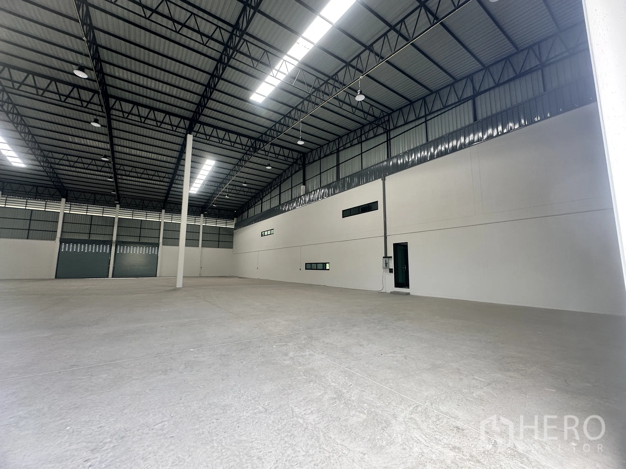 Factory for rent or sale in Bang Len, Nakhon Pathom - Warehouse corner with a personnel door, small windows, and a clean concrete floor.