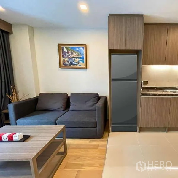 คอนโด ให้เช่า - มุมนั่งเล่นข้างครัวขนาดกะทัดรัดพร้อมตู้เย็นและโซฟา