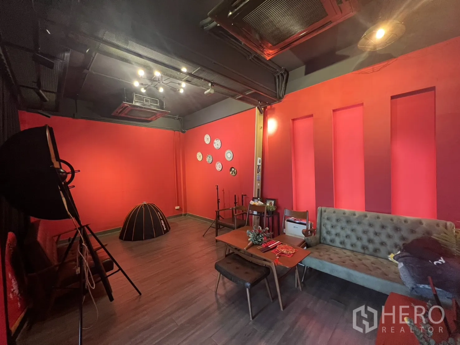 零售空间 出租在Watthana, Bangkok - 红色墙面工作室/休息区，沙发、灯具与吊顶空调。