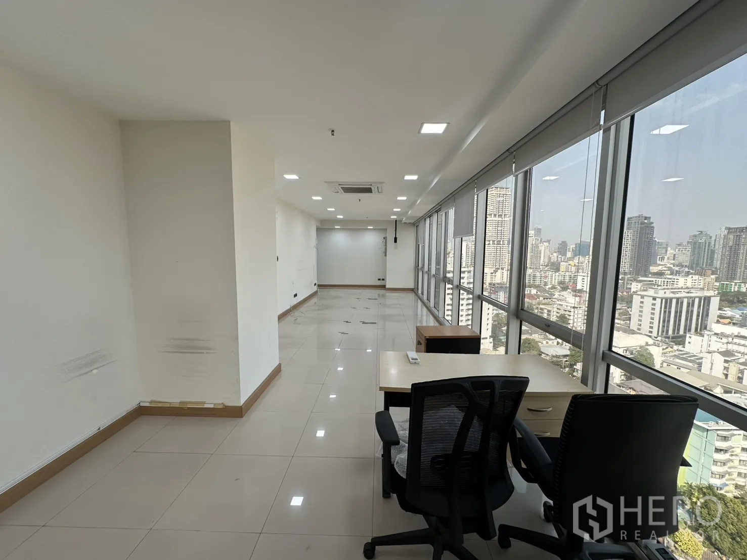 Office Space for rent - Desk setup beside full-height windows overlooking the cityscape.