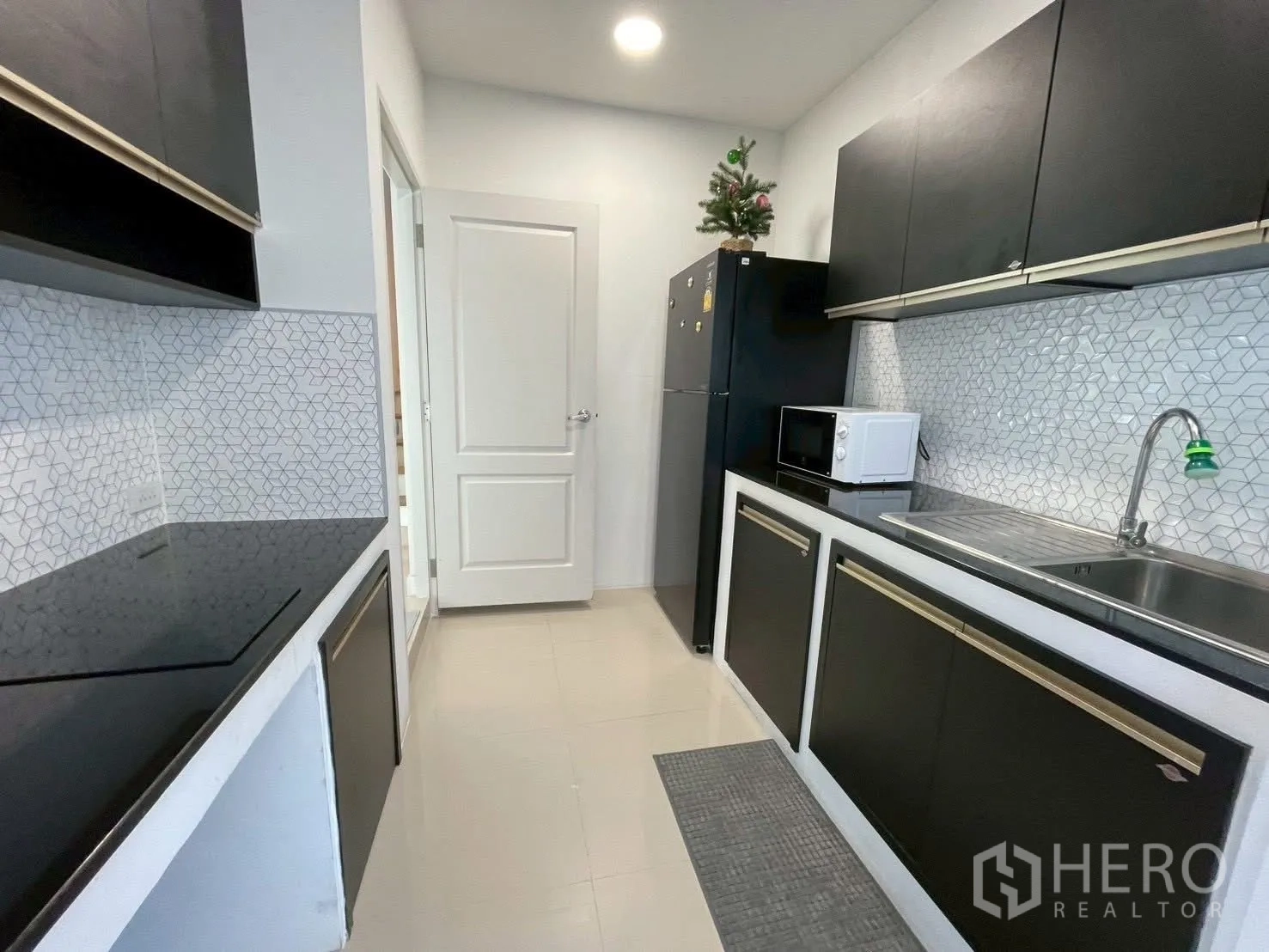 Detached House for rent in Prawet, Bangkok - Compact kitchen with black cabinets, tiled backsplash, sink, fridge and microwave.
