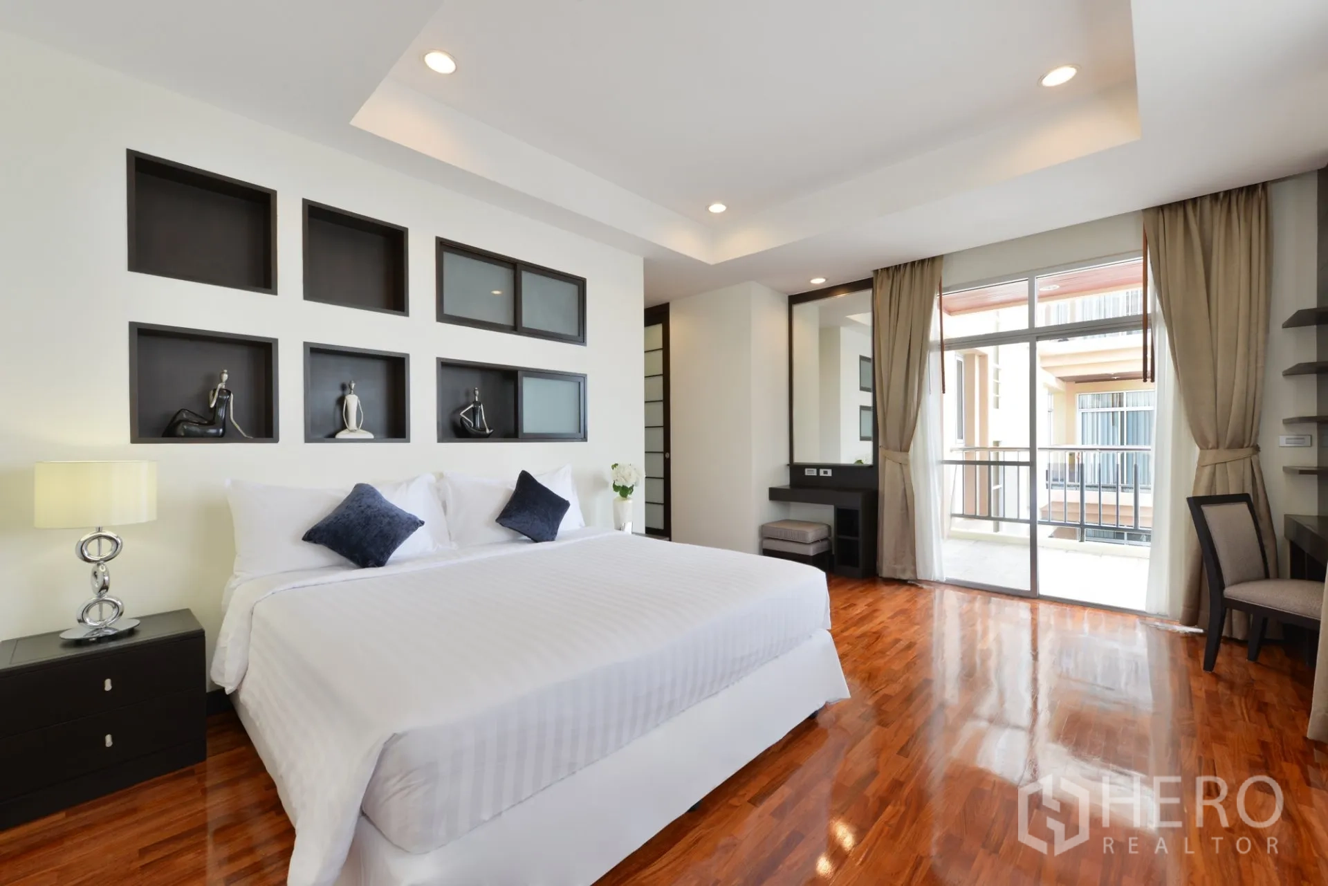 Apartment for rent in Watthana, Bangkok - Bright bedroom with hardwood floors, balcony access, built-in vanity, and large windows.