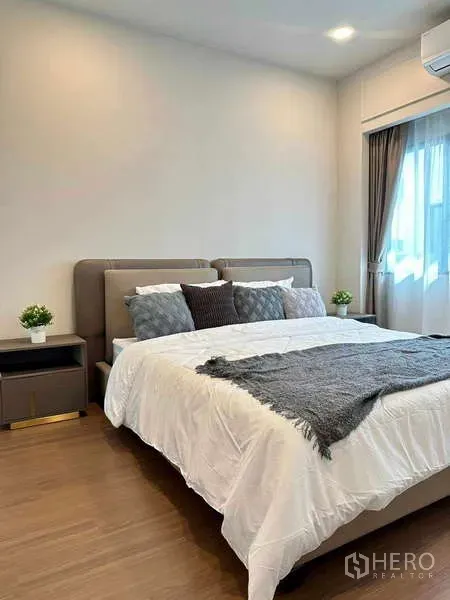 Detached House for rent or sale in Bang Phli, Samut Prakan - Cozy bedroom with upholstered bed, bedside tables, large window and warm wood floors.