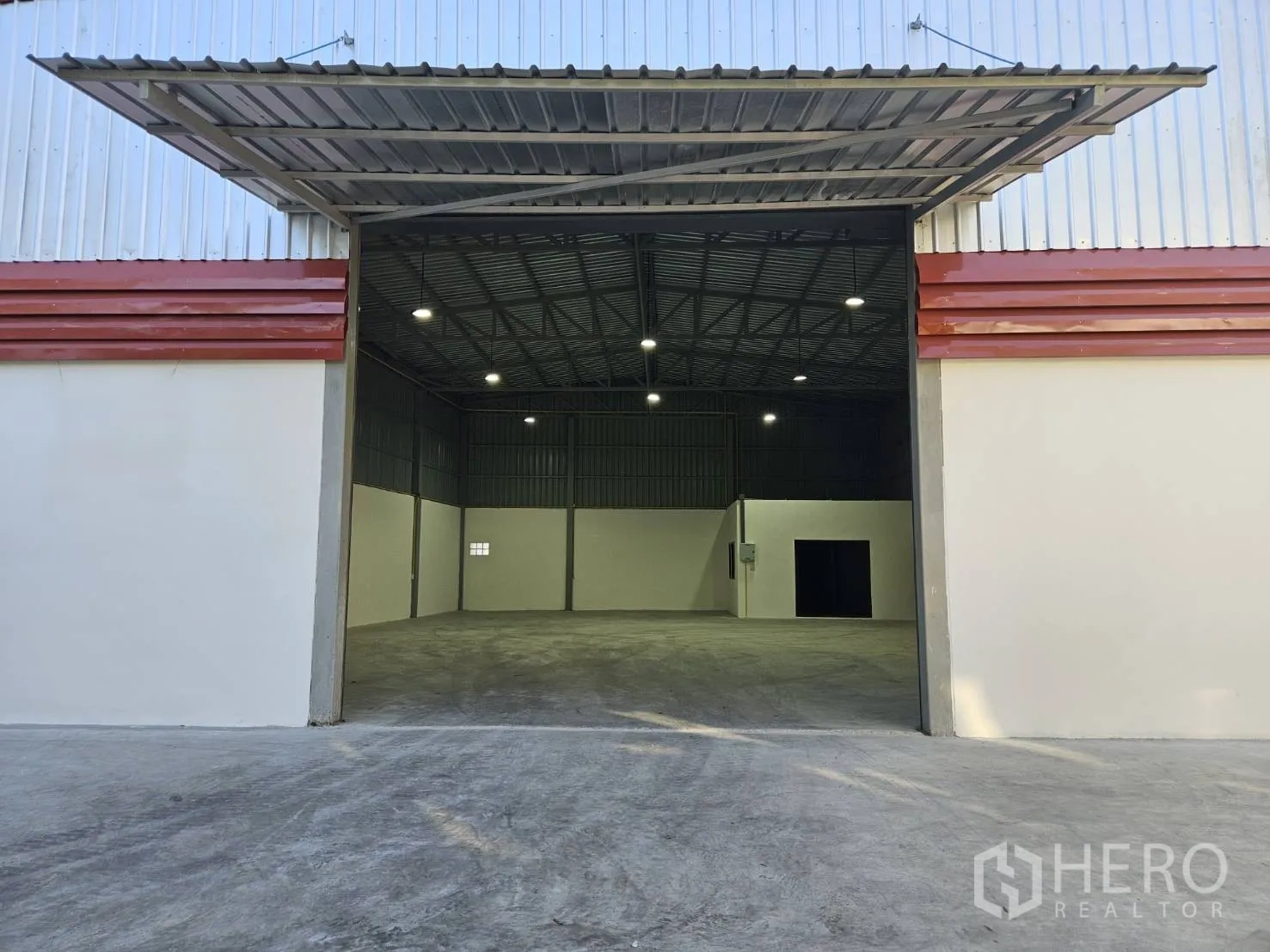 โกดัง for rent in Mueang Samut Prakan, Samut Prakan - ประตูโกดังขนาดใหญ่มีหลังคาคลุม ทางลาดคอนกรีตและภายในเปิดไฟสว่าง