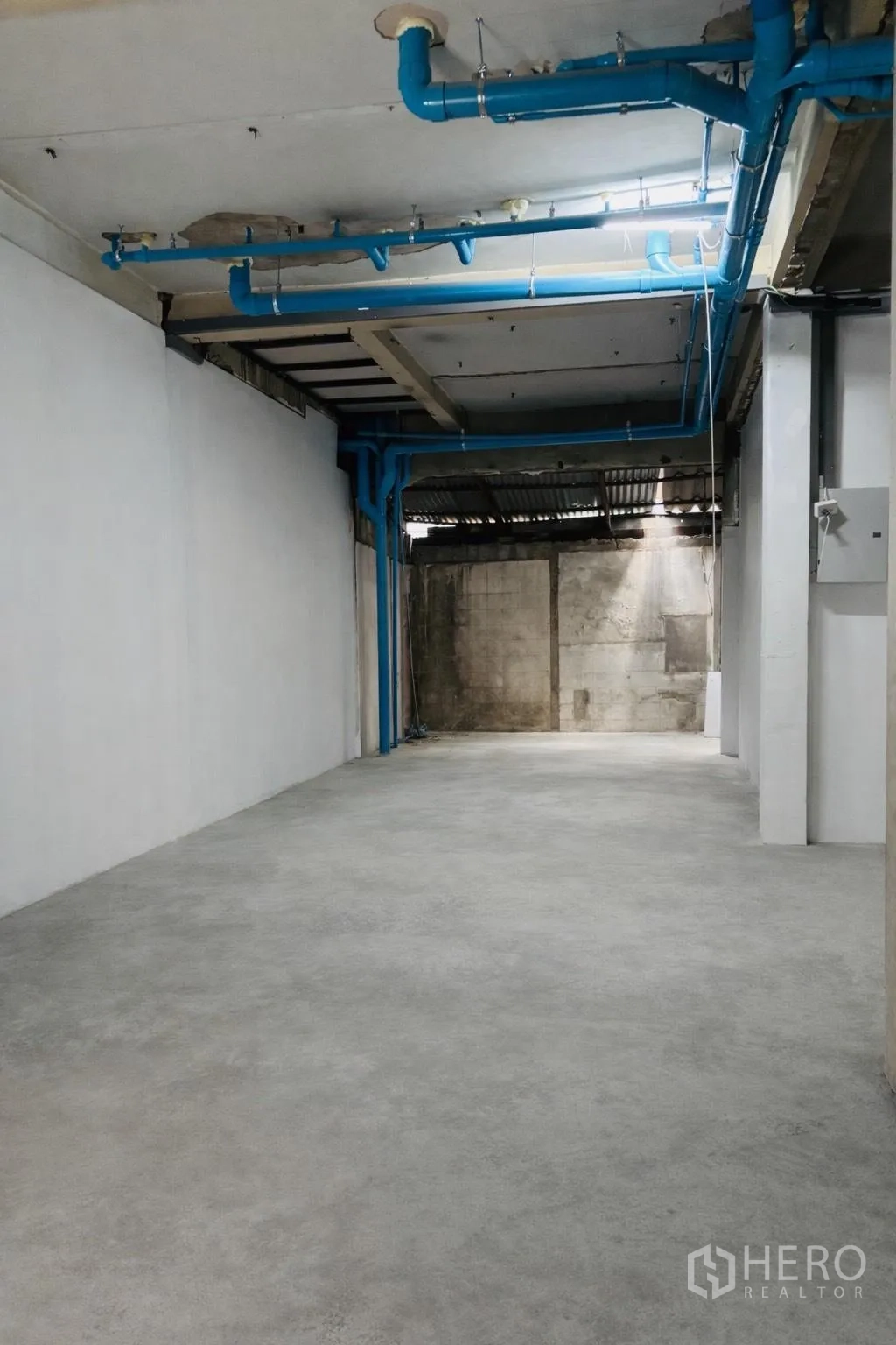 พื้นที่ขายของ for rent in Watthana, Bangkok - พื้นที่ภายในโล่ง พื้นคอนกรีต ผนังสีขาว และท่อสีน้ำเงินบนเพดาน.