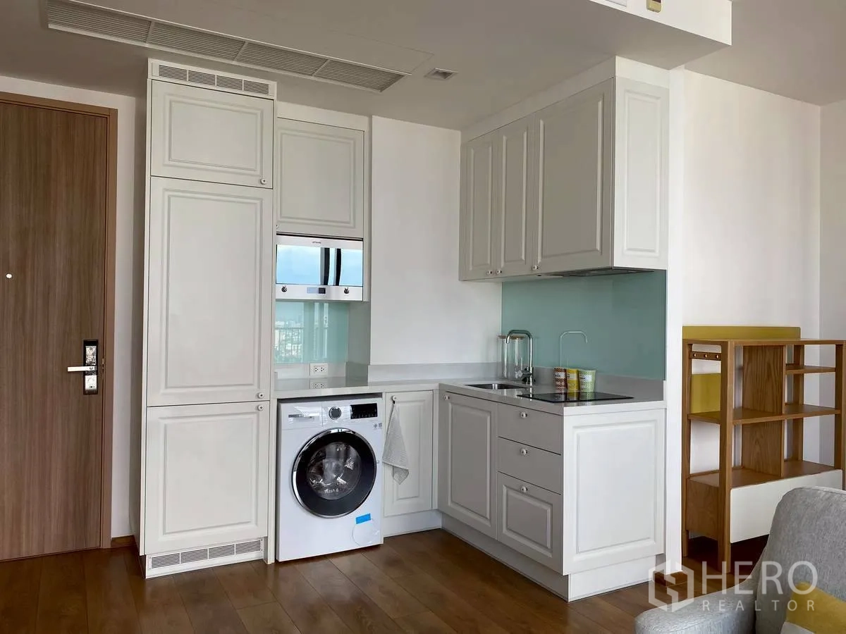 Condominium for rent in Watthana, Bangkok - Compact kitchen with white cabinetry, washing machine, and built-in appliances.