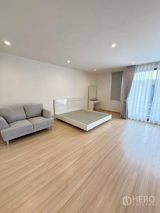 ทาวน์เฮาส์ ให้เช่าในSuan Luang, Bangkok - ห้องนอนใหญ่กว้าง ฐานเตียง โซฟา และโต๊ะเครื่องแป้ง ใกล้ประตูกระจกออกระเบียง