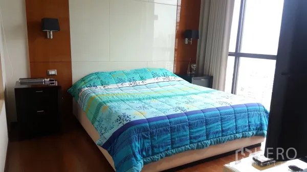 公寓 出租或出售在Khlong Toei, Bangkok - 主卧配落地窗与木质墙面，双人床铺蓝色被套。