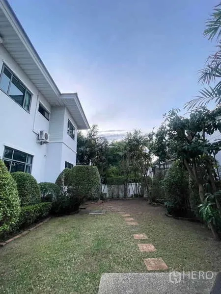 独立式住宅 出租在Mueang Nonthaburi, Nonthaburi - 侧院草坪与踏步道，整齐的灌木围合在房侧。