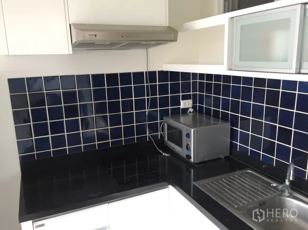 คอนโด ให้เช่าในKhlong Toei, Bangkok - ครัวแยก เคาน์เตอร์สีเข้ม ผนังกระเบื้องสีน้ำเงิน เตา เครื่องดูดควัน ไมโครเวฟ และอ่างล้างจาน
