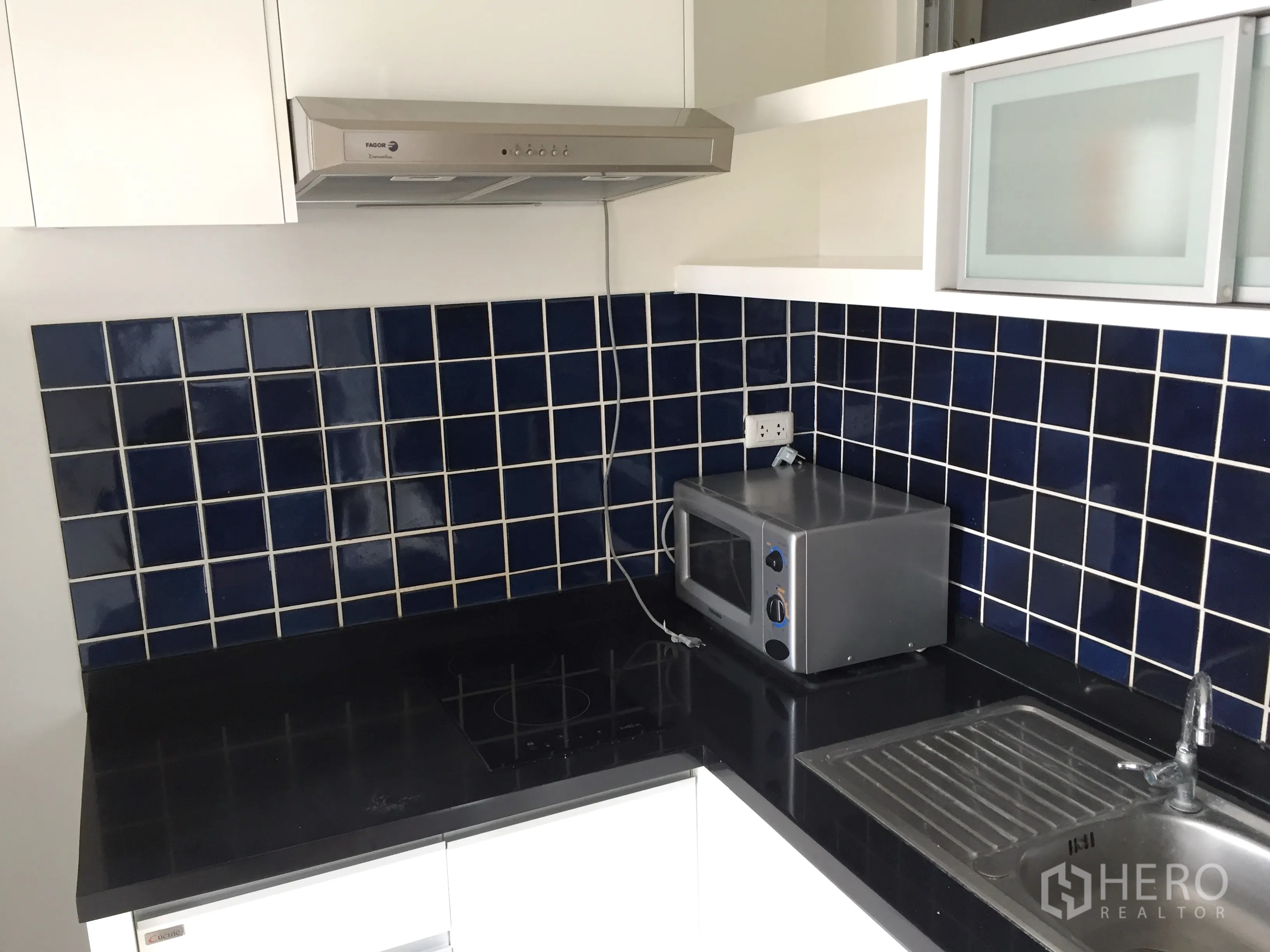 คอนโด ให้เช่าในKhlong Toei, Bangkok - ครัวแยก เคาน์เตอร์สีเข้ม ผนังกระเบื้องสีน้ำเงิน เตา เครื่องดูดควัน ไมโครเวฟ และอ่างล้างจาน