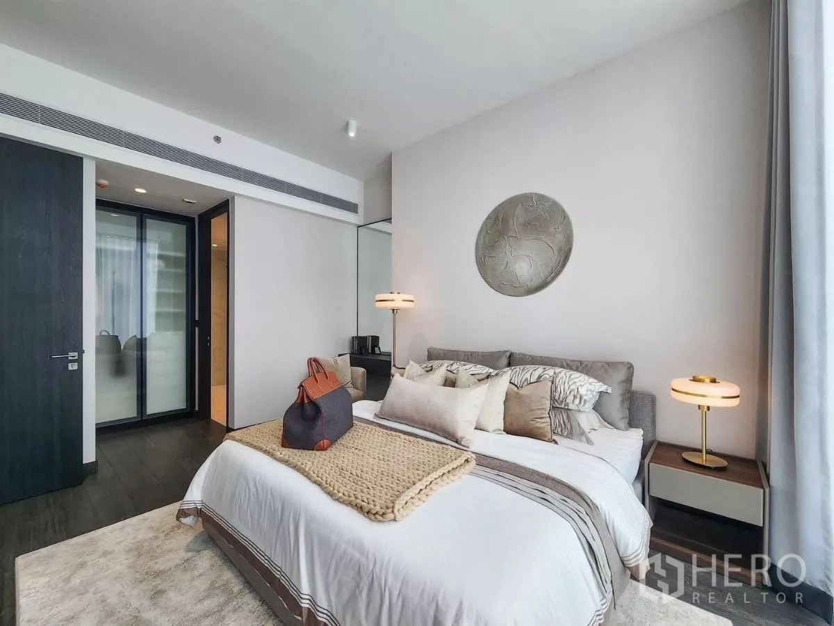 公寓 出租在Bang Rak, Bangkok - 卧室角度展示床、床头灯与玻璃推拉衣柜门。