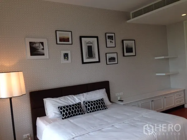 คอนโด ให้เช่าหรือขายในPathum Wan, Bangkok - ห้องนอนอบอุ่น เตียงผ้าปูสีขาว วอลล์เปเปอร์ลายกราฟิก กรอบรูป และตู้บิวท์อินพร้อมชั้นวาง.