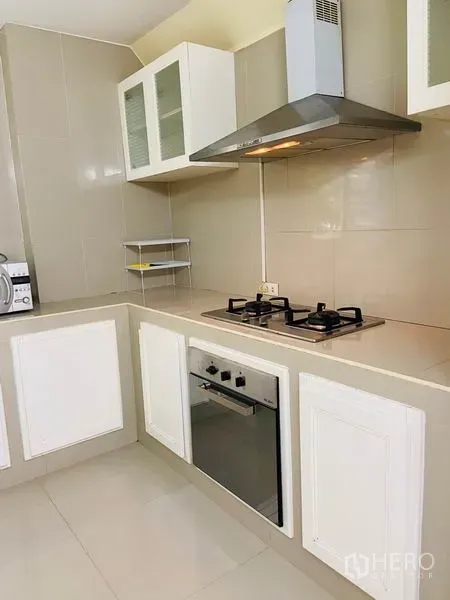 บ้าน ให้เช่าในWatthana, Bangkok - ครัวรูปตัวแอล เตาแก๊ส เตาอบ เครื่องดูดควัน และตู้บิ้วท์อินสีขาว