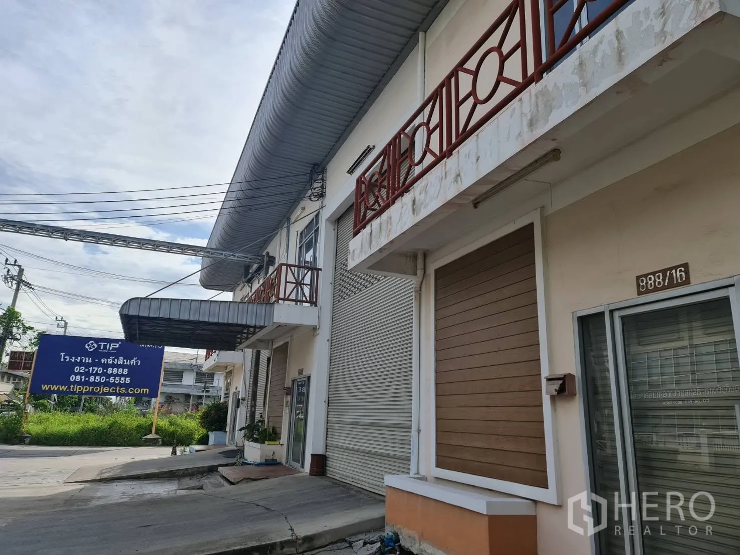 Factory for rent or sale in Bang Phae, Ratchaburi - Factory frontage with sliding glass entrance, canopy, and adjacent roller door.