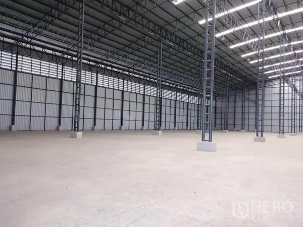 工厂 出租在Mueang Samut Prakan, Samut Prakan - 仓库分区斜角视图，钢柱林立，带百叶通风带与明亮照明。