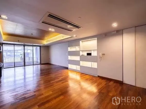 Condominium for sale in Yan Nawa, Bangkok - Open living area with ceiling cassette air‑conditioning, illuminated display shelves and access to the balcony.