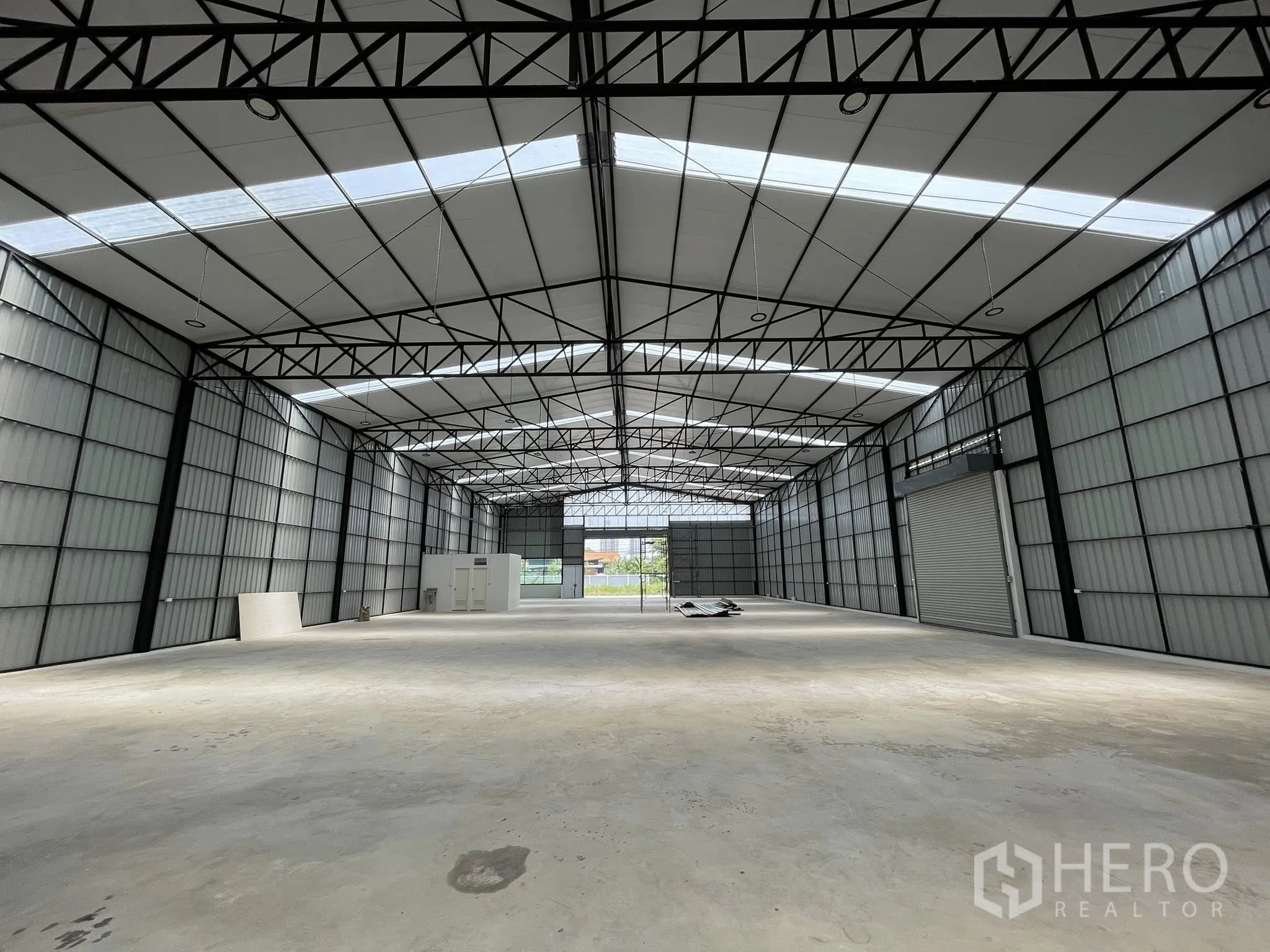 โกดัง for rent in Pak Kret, Nonthaburi - มุมมองลึกของพื้นที่ภายใน พื้นคอนกรีต และประตูม้วนด้านใน