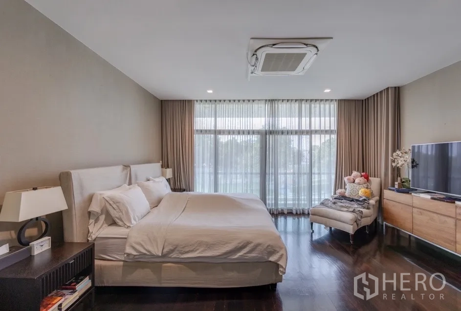 Detached House for rent or sale in Bang Kapi, Bangkok - Master bedroom with king bed and floor-to-ceiling curtains.