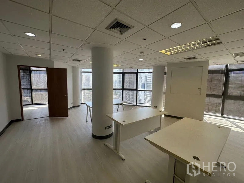 办公空间 出租 - 转角办公区，圆柱与工位，落地窗环绕俯瞰天际线。