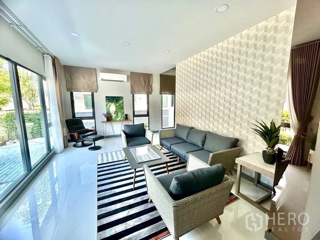 独栋房屋 for rent in Bang Phli, Samut Prakan - 明亮家庭客厅，通高玻璃与藤编沙发组合。