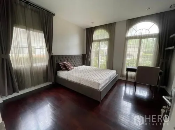Detached House for rent in Bang Phli, Samut Prakan - Bright bedroom with arched windows, wood flooring and a study desk.