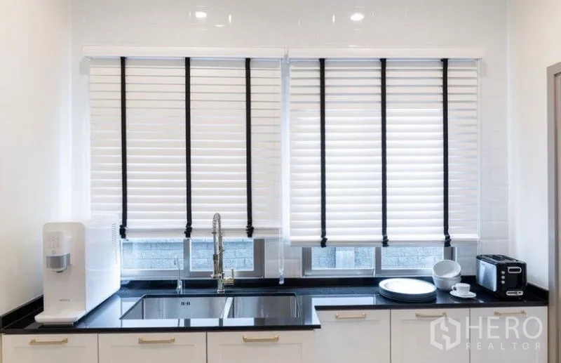 Detached House for rent or sale in Saphan Sung, Bangkok - Kitchen sink zone with black countertop, double basin, white cabinets, and blinds.