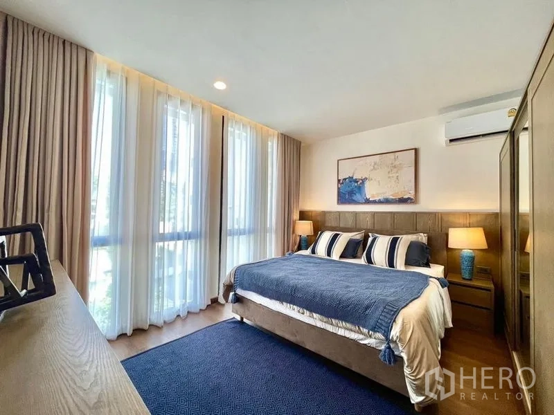 Townhouse for rent - Sunlit bedroom with floor-to-ceiling curtains, blue accents, and air conditioning.