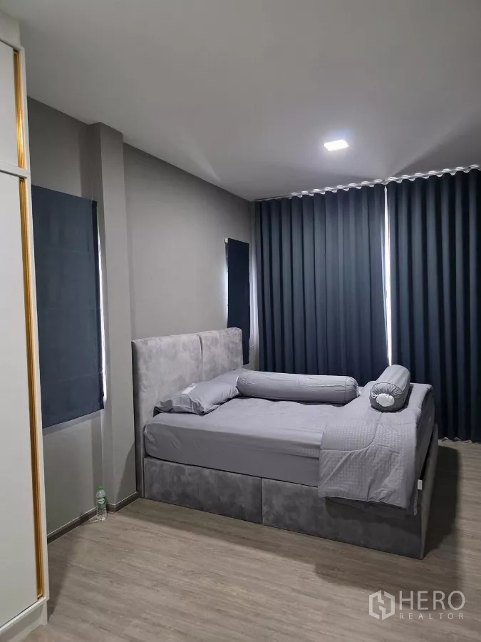Detached House for rent in Bang Phli, Samut Prakan - Cozy bedroom with upholstered bed, blackout curtains and wood-look flooring.
