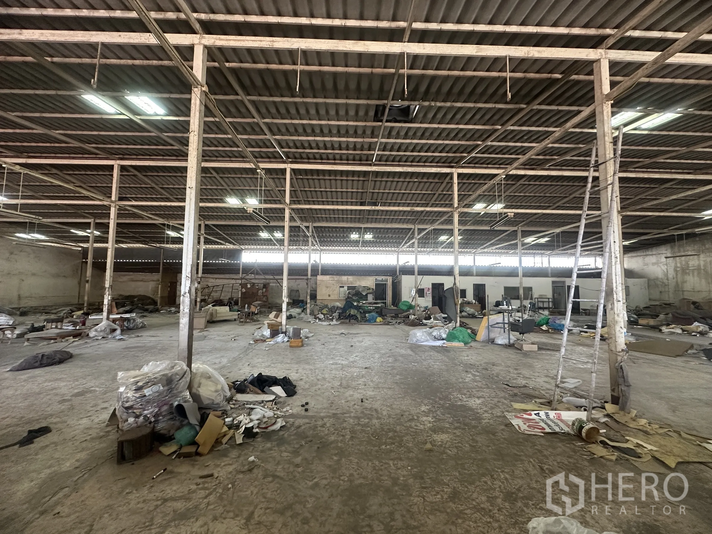 Warehouse for rent in Lam Luk Ka, Pathum Thani - Central hall with concrete floor and ladder near workspace partitions.