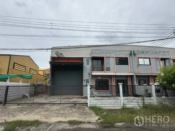 คลังสินค้า ให้เช่าหรือขายในBang Yai, Nonthaburi - ด้านหน้าคลังสินค้า 2 ชั้น พร้อมประตูม้วนขนาดใหญ่และลานจอดรถ ในบางใหญ่ นนทบุรี