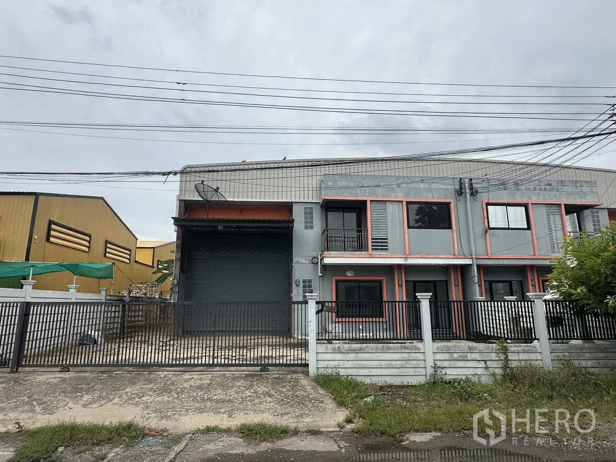 คลังสินค้า ให้เช่าหรือขายในBang Yai, Nonthaburi - ด้านหน้าคลังสินค้า 2 ชั้น พร้อมประตูม้วนขนาดใหญ่และลานจอดรถ ในบางใหญ่ นนทบุรี