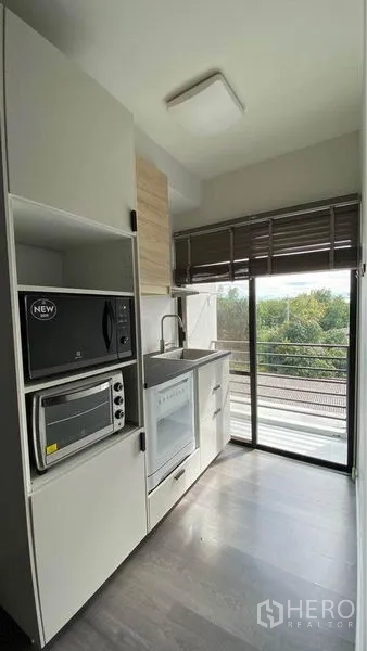 零售空间 出售在Bang Na, Bangkok - 紧凑型茶水间，内置微波炉、烤箱与水槽，旁连推拉玻璃门与绿景。