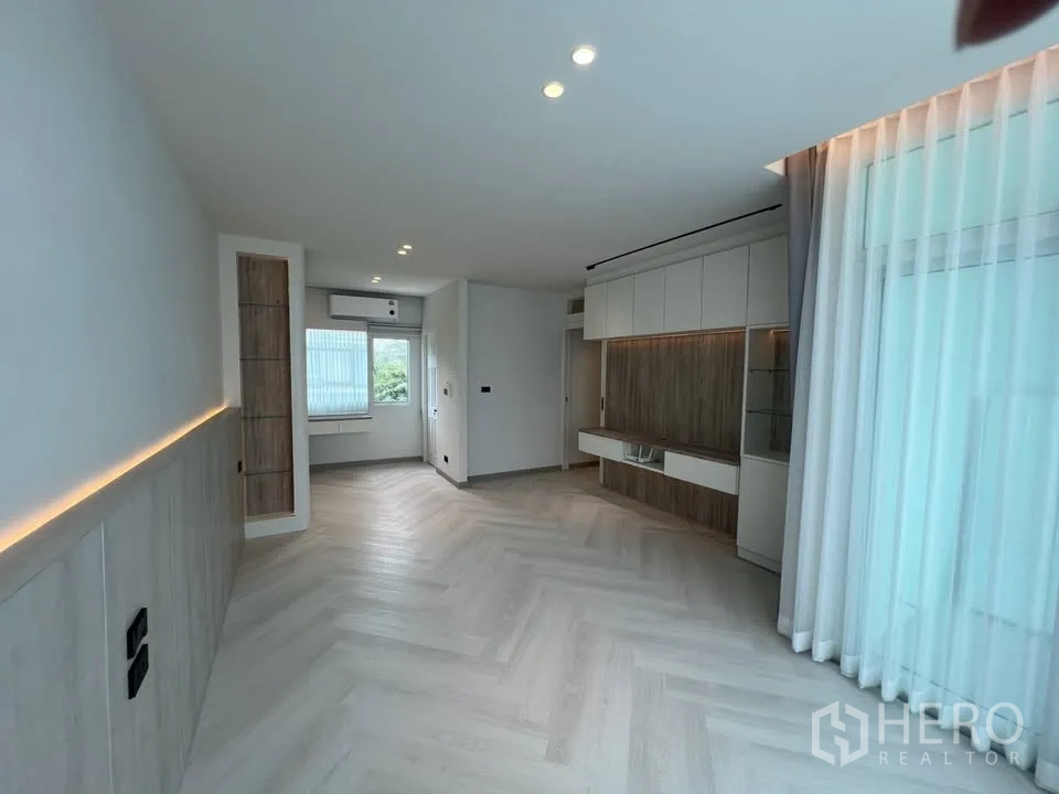 Townhouse for rent in Prawet, Bangkok - Open living area with built-in media wall, windows and sheer drapes.