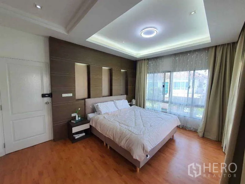 Detached House for rent in Saphan Sung, Bangkok - Master bedroom with feature wall panels, large windows and soft ceiling lighting.