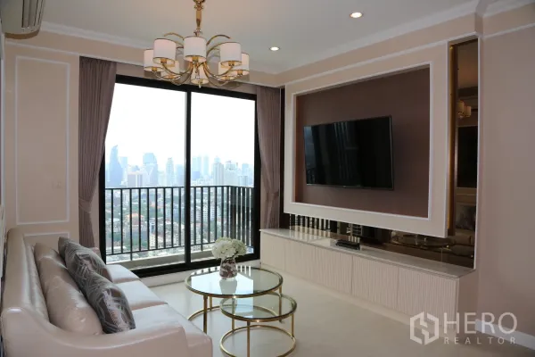 Condominium for rent in Huai Khwang, Bangkok - Living room with floor-to-ceiling sliding doors to a balcony overlooking the Bangkok skyline, TV feature wall and round glass coffee tables.