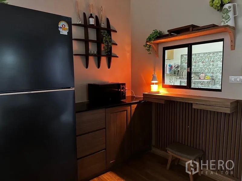 独立式住宅 出租在Prawet, Bangkok - 备餐区，黑色冰箱、木柜、微波炉与传菜窗。