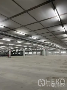 Factory for rent in Phra Pradaeng, Samut Prakan - Angled view of spacious warehouse bay with suspended ceiling panels and columns.