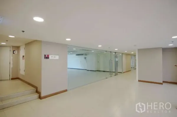 Office Space for rent - Well-lit corridor with glass-walled office entrance and double doors.