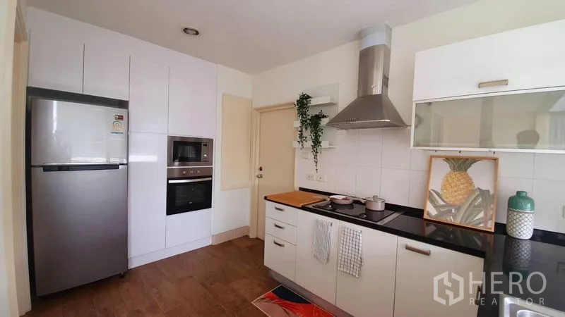 คอนโด ให้เช่าในWatthana, Bangkok - ห้องครัวสว่าง ตู้สีขาว เคาน์เตอร์ท็อปสีดำ เครื่องดูดควัน และเครื่องใช้สแตนเลส