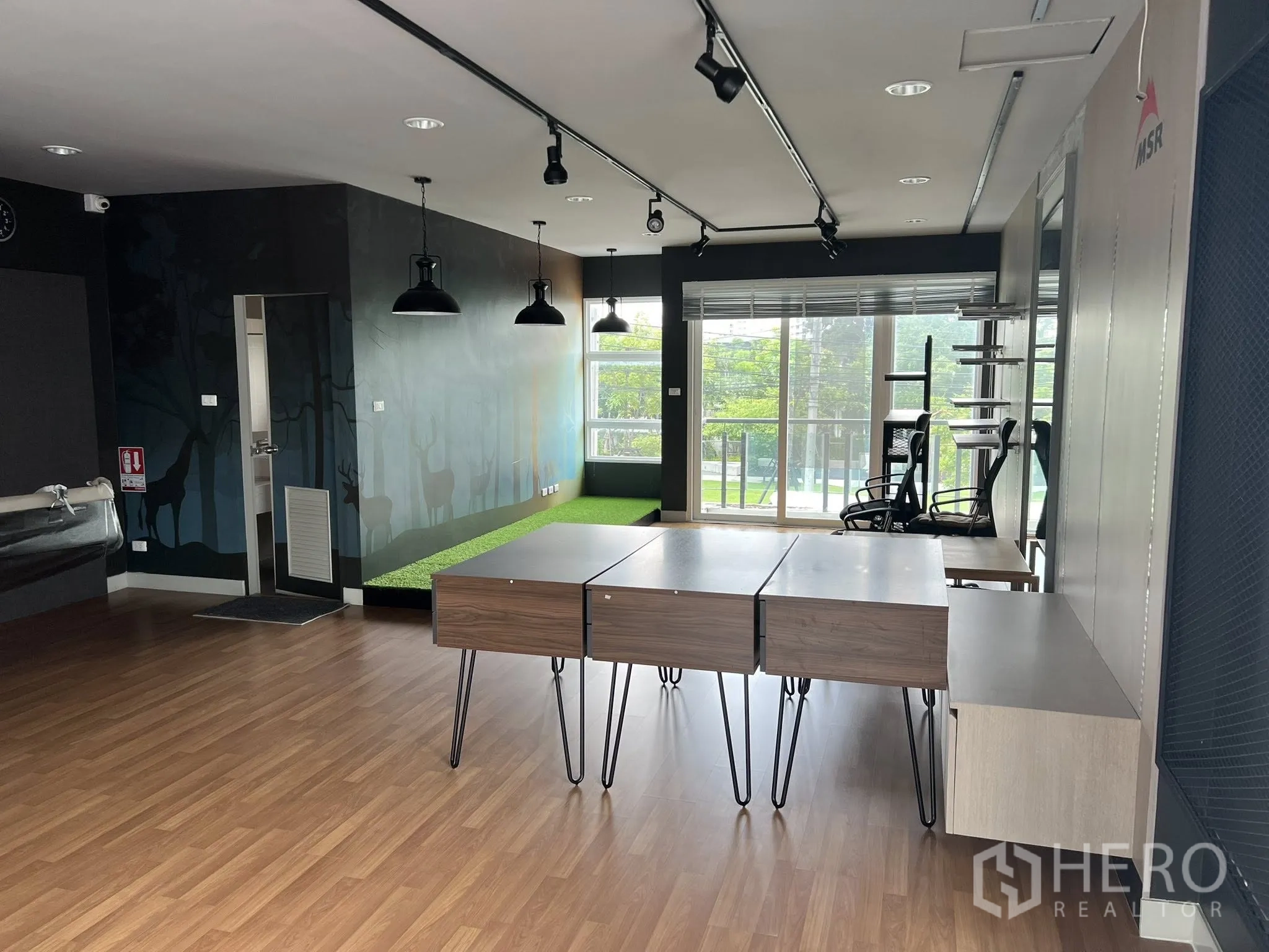Detached House for rent or sale in Don Mueang, Bangkok - Open-plan office with wood floors, track lights and balcony windows.