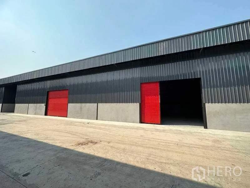คลังสินค้า ให้เช่าในKhlong Sam Wa, Bangkok - มุมมองด้านหน้าโกดังอีกด้าน ประตูม้วนสีแดงและลานโหลดกว้าง