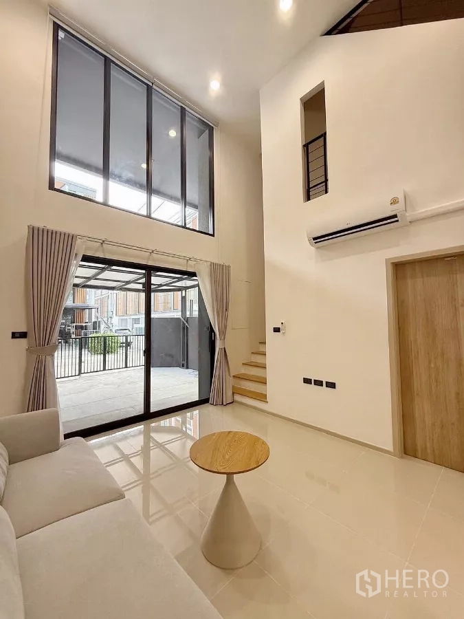 ทาวน์เฮาส์ ให้เช่าในSuan Luang, Bangkok - พื้นที่นั่งเล่นสว่างด้วยหน้าต่างสูงและประตูกระจกบานเลื่อนออกสู่ที่จอดรถ