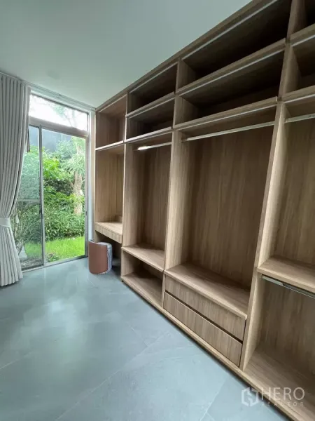 独立式住宅 出租在Saphan Sung, Bangkok - 步入式衣帽间，整面木质柜体，透过推拉玻璃门可见花园。