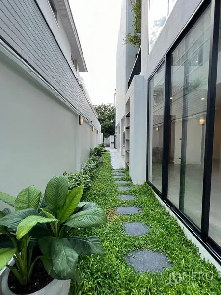 สำนักงานที่บ้าน ขายในPhra Khanong, Bangkok - สวนข้างบ้านจัดแต่งด้วยแผ่นทางเดิน ถัดจากผนังกระจกของตัวบ้าน.