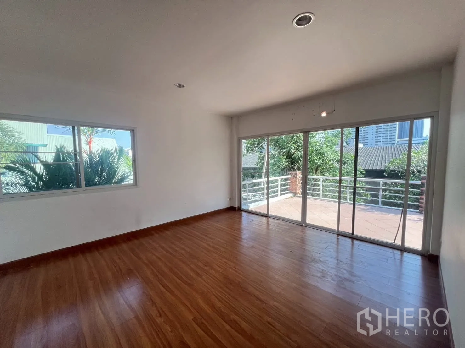 Detached House for rent in Watthana, Bangkok - Upper-floor bedroom with wood floors and sliding doors to a big balcony.