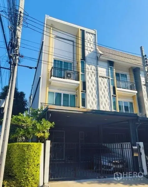 联排别墅 出售在Mueang Nonthaburi, Nonthaburi - 联排别墅立面，几何装饰、绿篱与车道大门