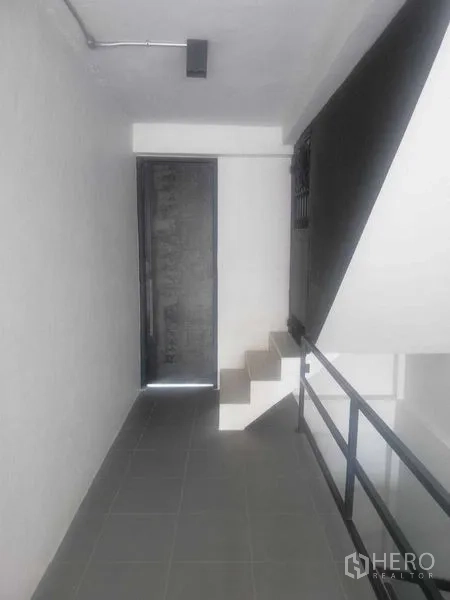 Shophouse for rent in Khlong Toei, Bangkok - Mezzanine corridor with metal handrail and a door leading to upper rooms.